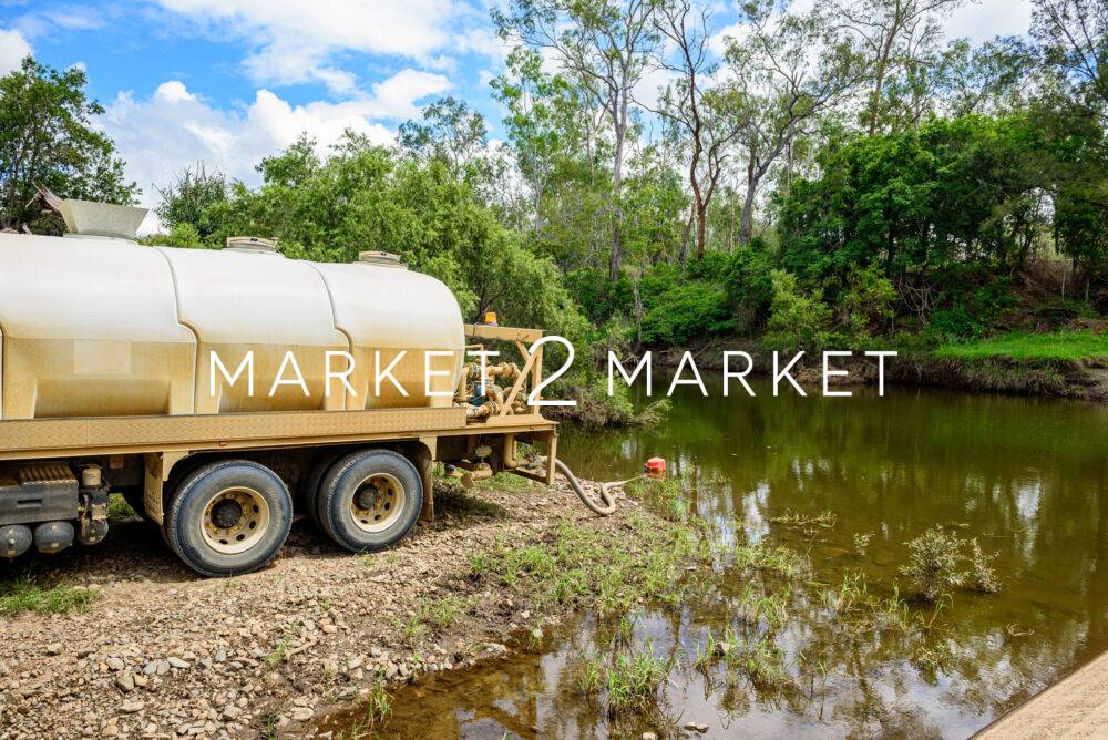 Tanker truck pumping fresh water from a creek next to a concrete
